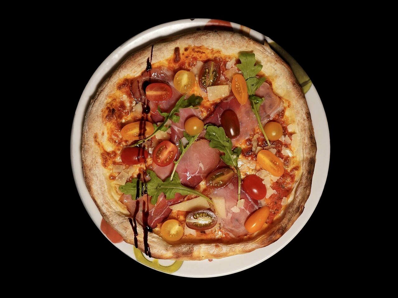 Pizza cuite au four du Restaurant L’Étoile, jambon cru, roquette et tomates cerises